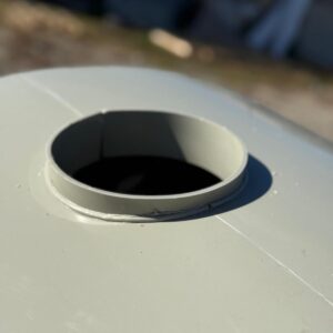 Gură deschisă pe suprafață metalică circulară, luminată.