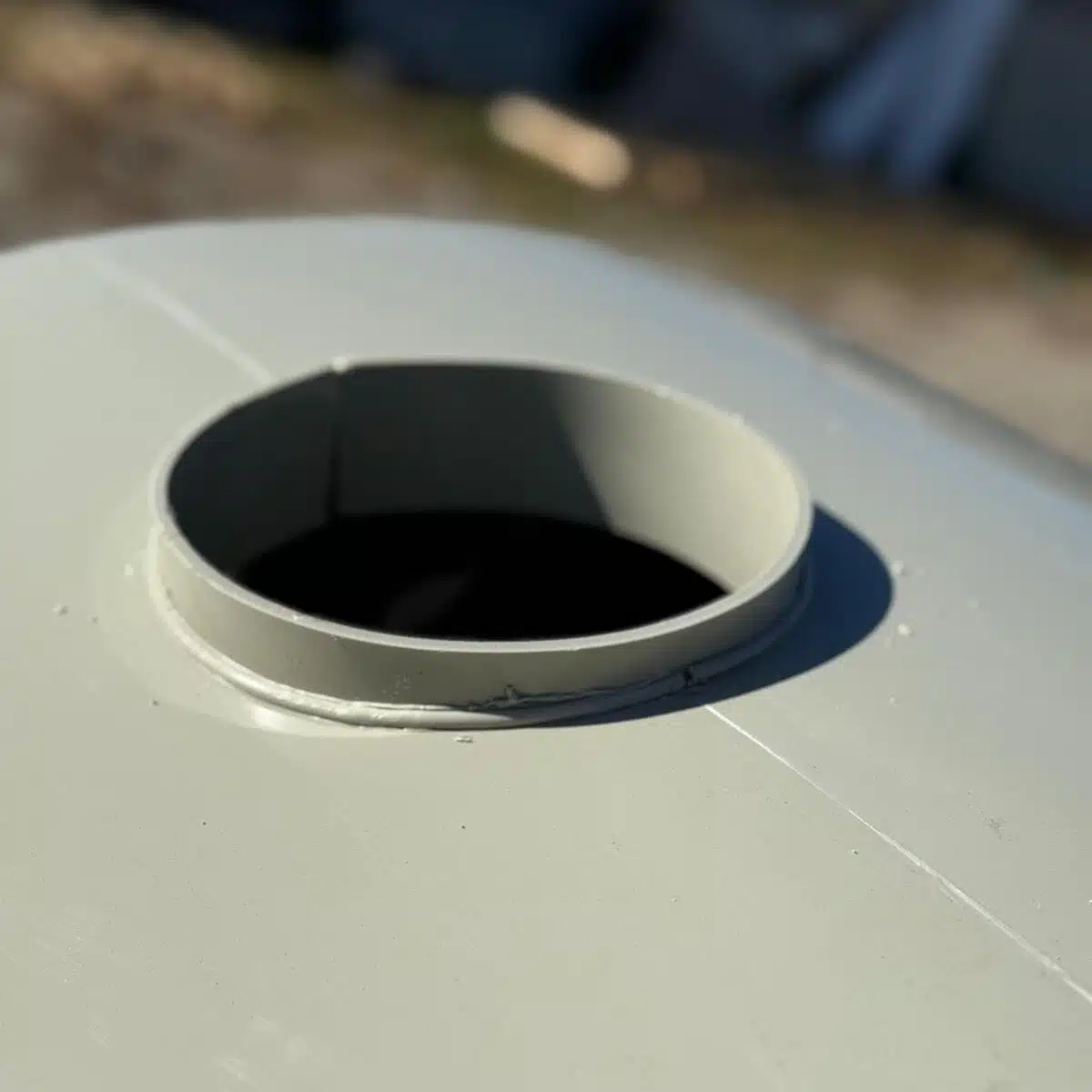 Gură deschisă pe suprafață metalică circulară, luminată.